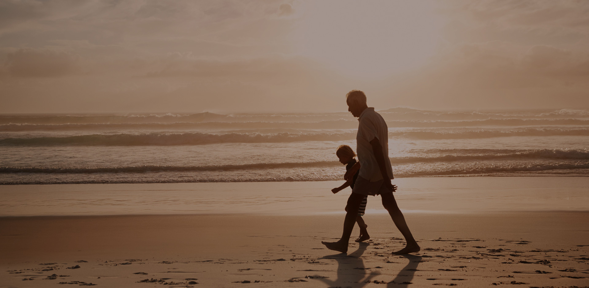 Grandfather and grandchild walking on beach